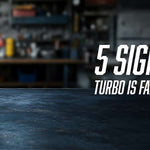 Cut-away diesel turbocharger with red compressor housing displayed on a workshop bench, showing internal compressor wheel and bearing assembly. Text reads: 5 Signs Your Truck Turbo Is Failing