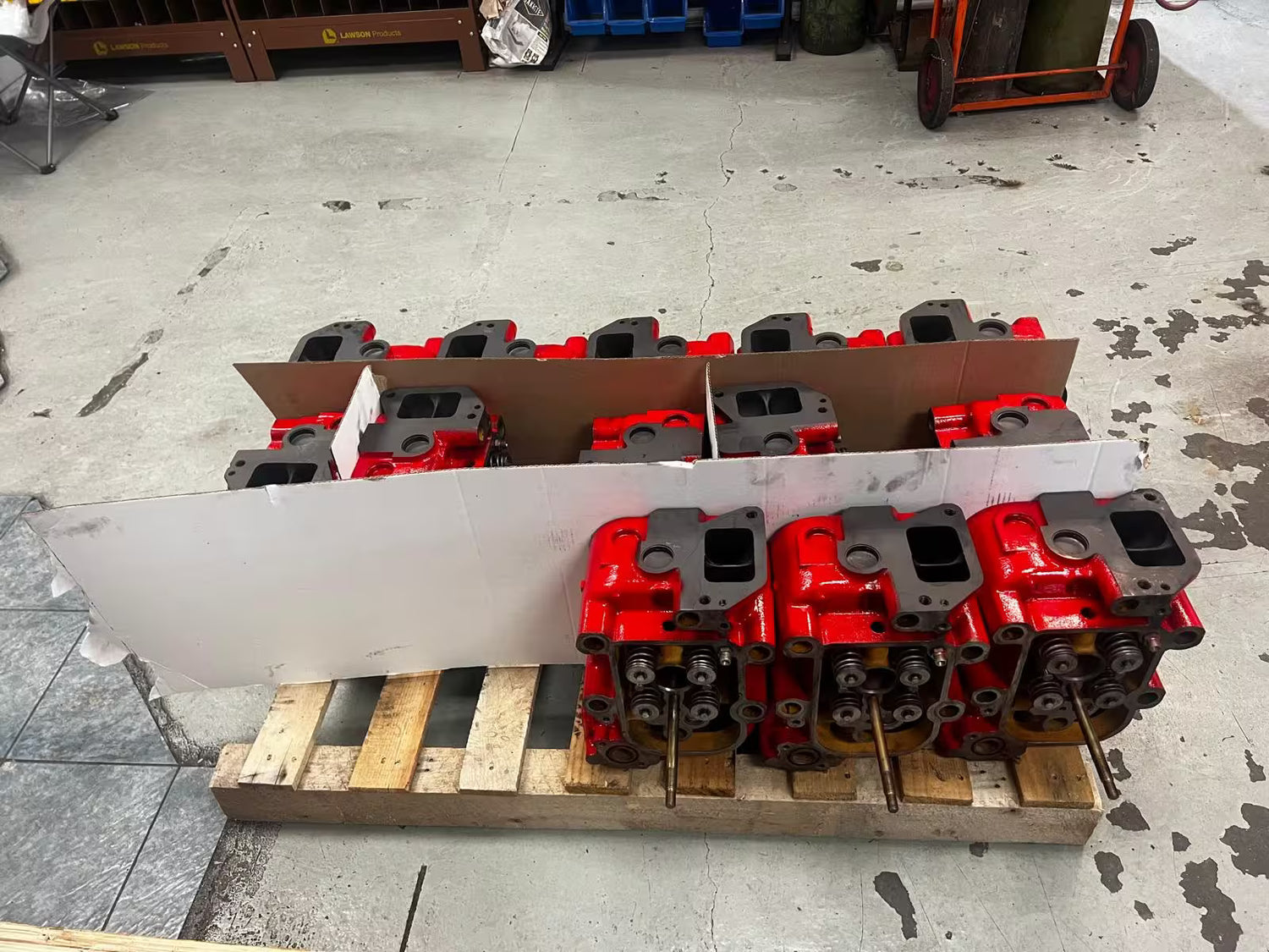 Red and black mechanical components on a wooden pallet in an industrial setting