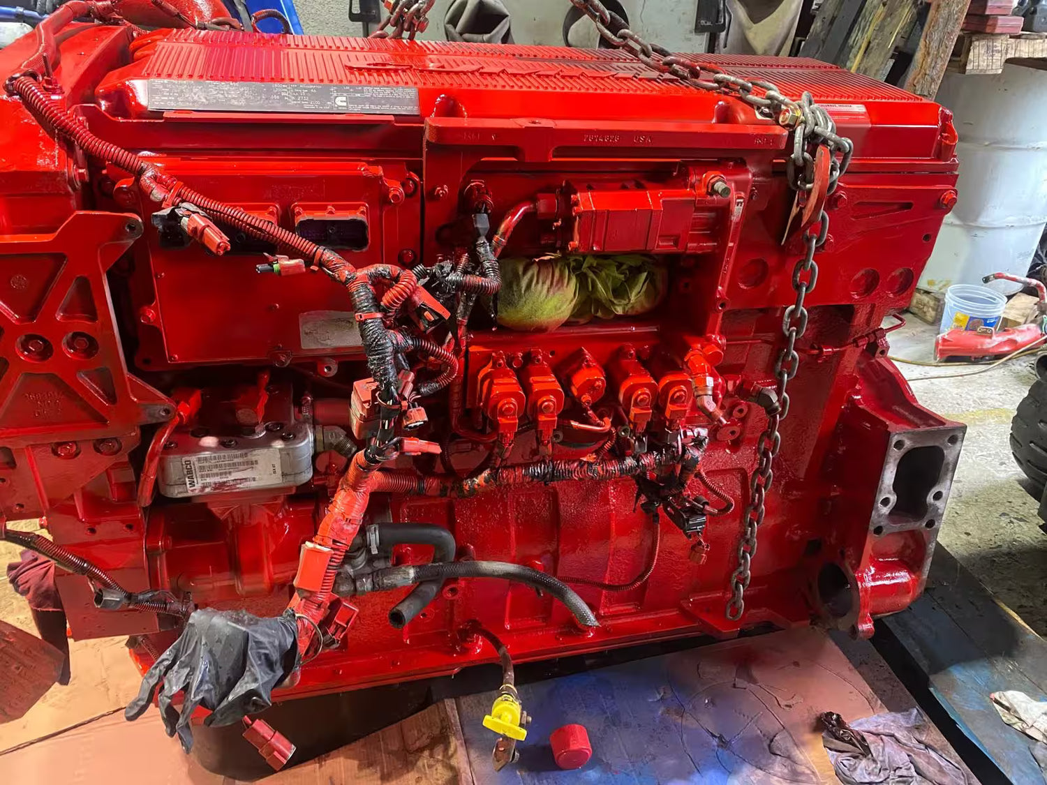 Red engine block with visible components on a workshop floor.
