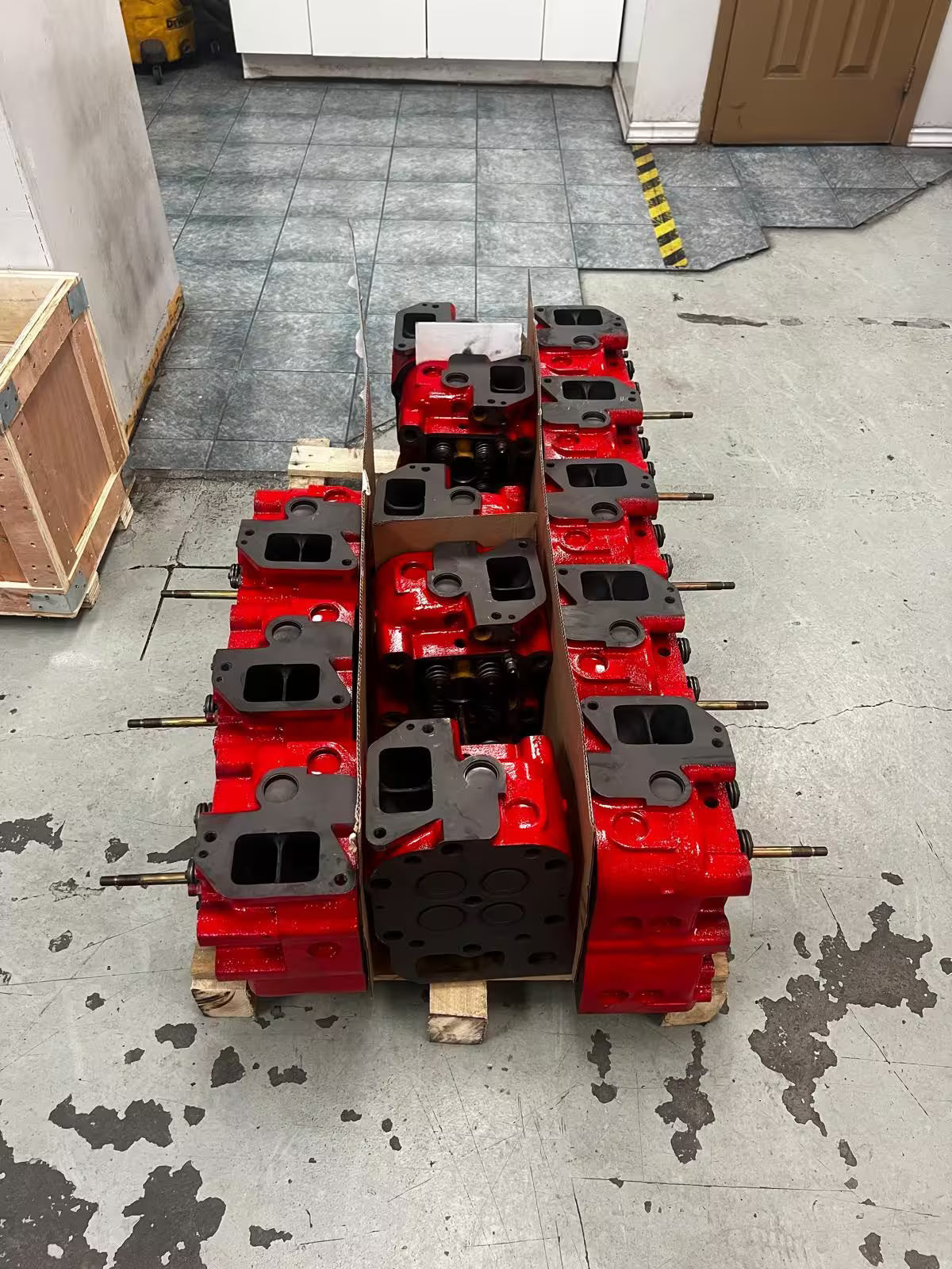 Stack of red mechanical parts on a pallet in an indoor setting
