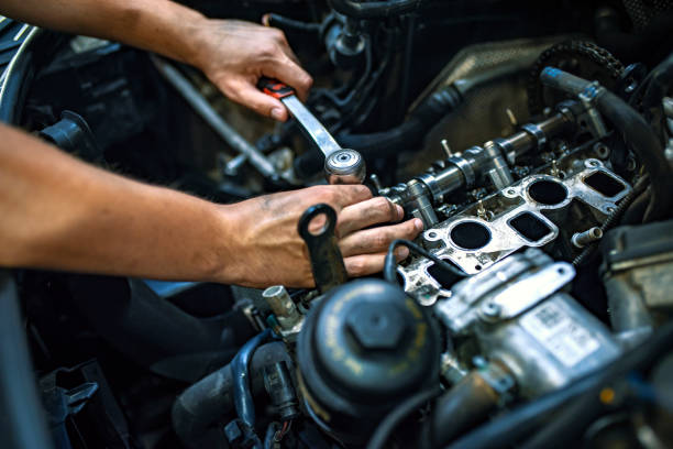 Person working on a car engine with tools