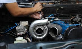 Person working on a car engine with a turbocharger