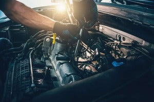 Person working on a car engine with tools