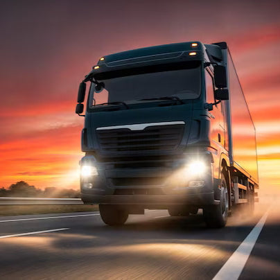 Truck driving on a road with a sunset sky